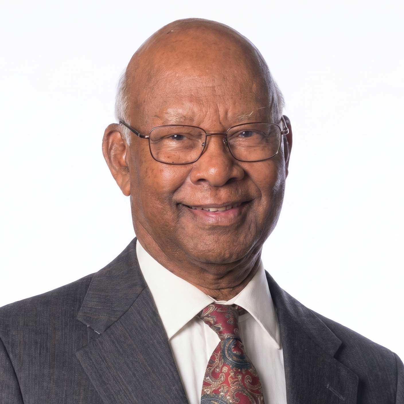 Man wearing glasses, a suit, and a patterned tie on a white background