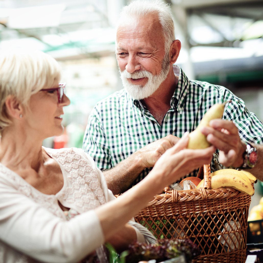 an old couple holding fruits