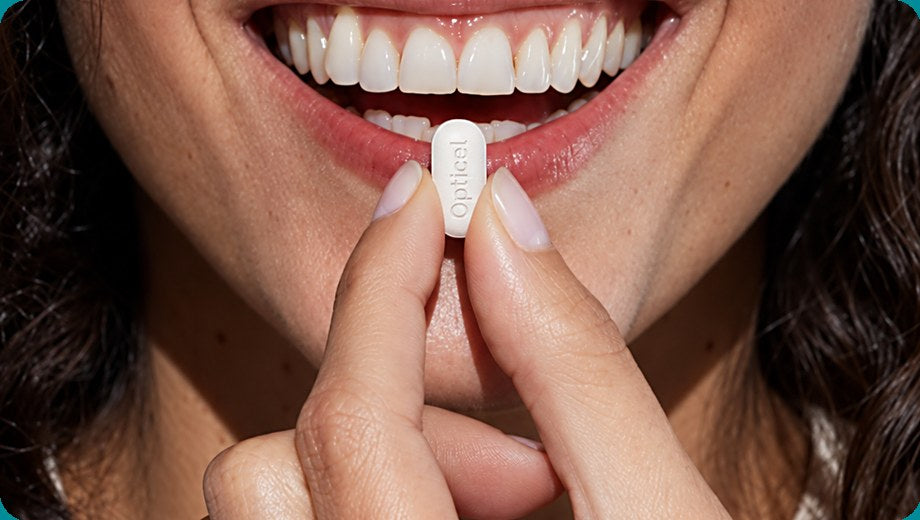 Woman holding an OptiCel caplet to her lips
